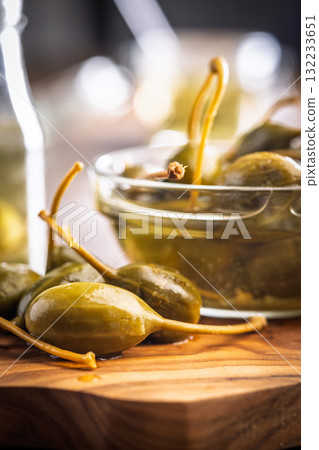 Pickled capers berries on wooden cutting board. Pickled capers berries on wooden cutting board. 132233651