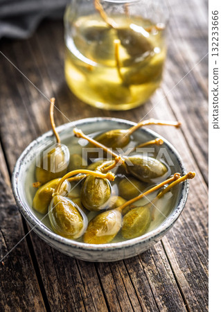 Pickled capers berries in bowl on wooden table. Pickled capers berries in bowl on wooden table. 132233666