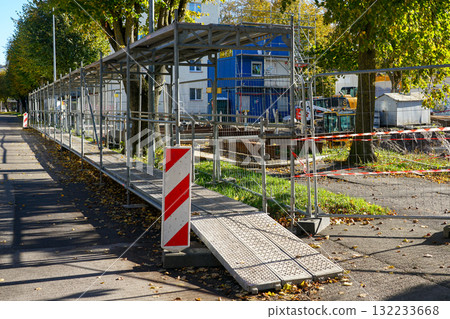 Safe temporary pedestrian walkway with metal scaffolding along urban construction site in autumn Safe temporary pedestrian walkway with metal scaffolding along urban construction site in autumn 132233668