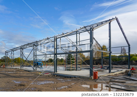 Steel structure framework of industrial warehouse building under construction on a clear blue day Steel structure framework of industrial warehouse building under construction on a clear blue day 132233679
