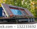 Prefabricated building wall with red-framed window transported on trailer at construction site 132233692