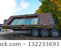 Prefabricated brick wall with red-framed windows secured on trailer for transport at construction site 132233693