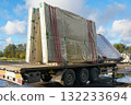 Prefabricated concrete wall panels wrapped in plastic and secured on flatbed truck trailer for transport 132233694