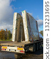 Prefabricated concrete wall panels wrapped and secured on flatbed trailer at construction logistics site 132233695