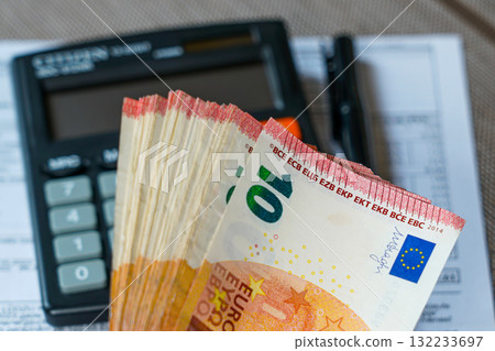 Stack of ten euro banknotes with calculator and documents symbolizing finance, accounting, and savings 132233697