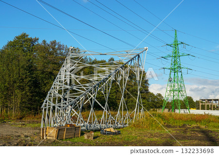 New power transmission tower under construction with metal framework and green pylon on sunny day New power transmission tower under construction with metal framework and green pylon on sunny day 132233698