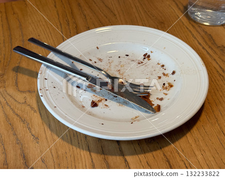 Empty messy dessert plate with crumbs and cutlery on wooden table. Satisfaction, simplicity, and everyday cafe moment after meal. Empty messy dessert plate with crumbs and cutlery on wooden table. Satisfaction, simplicity, and everyday cafe moment after meal. 132233822