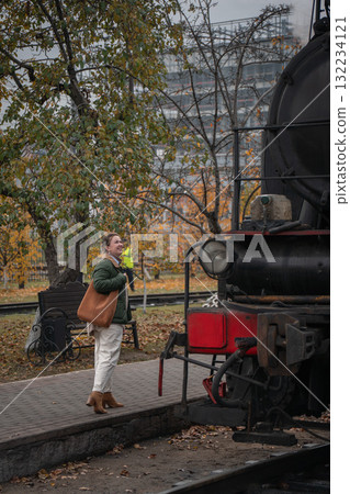 Woman in a green jacket stands near a vintage black steam locomotive at the Moscow Railway Museum Turntable Woman in a green jacket stands near a vintage black steam locomotive at the Moscow Railway Museum Turntable 132234121