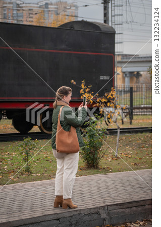 Woman in a green jacket takes a photo of a vintage black steam locomotive at the Moscow Railway Museum Turntable Woman in a green jacket takes a photo of a vintage black steam locomotive at the Moscow Railway Museum Turntable 132234124