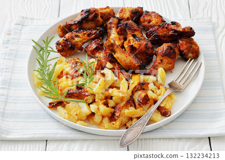 bbq chicken wings with fried potatoes on plate 132234213