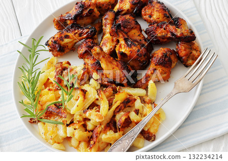 bbq chicken wings with fried potatoes on plate 132234214