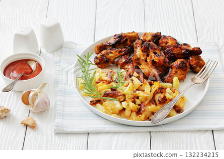 bbq chicken wings with fried potatoes on plate 132234215