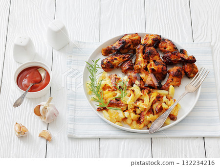 bbq chicken wings with fried potatoes on plate 132234216