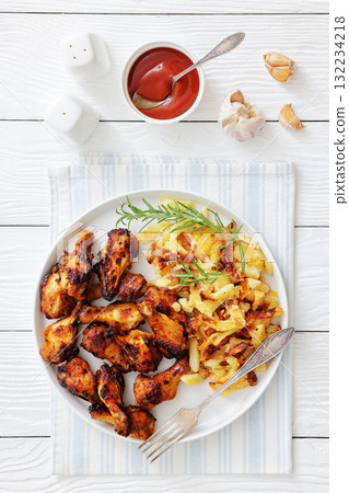 bbq chicken wings with fried potatoes on plate 132234218