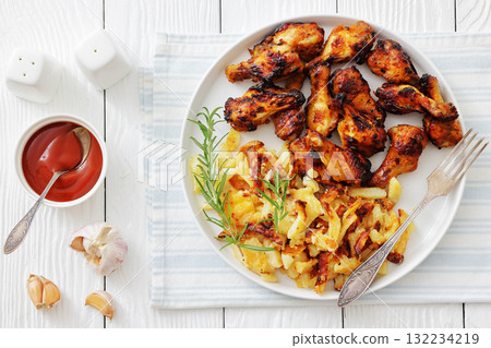 bbq chicken wings with fried potatoes on plate 132234219