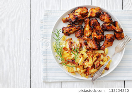 bbq chicken wings with fried potatoes on plate 132234220