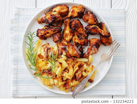 bbq chicken wings with fried potatoes on plate 132234221