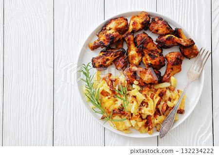 bbq chicken wings with fried potatoes on plate 132234222