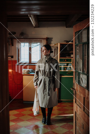 Woman standing in old rural kitchen with half-empty shopping bag. Woman standing in old rural kitchen with half-empty shopping bag. 132234229
