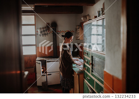 Woman washing dishes in an old rural kitchen. Woman washing dishes in an old rural kitchen. 132234233