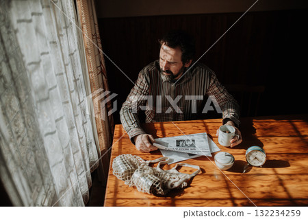 Portrait of poor despaired man sitting at table drinking tea. 132234259