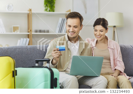 Couple using laptop and credit card for online travel booking at home together Couple using laptop and credit card for online travel booking at home together 132234493