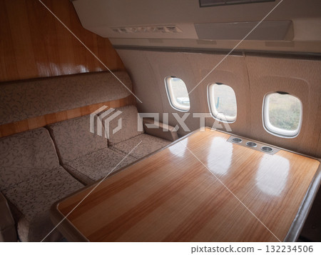 luxurious business setting, upscale jet meeting room setup, elegant private jet conference table with seating, sophisticated aircraft meeting area with plush seating and glossy surfaces 132234506