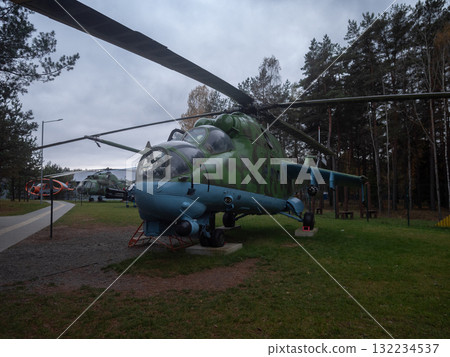 helicopter inspection display, museum exhibit features weathered helicopter with maintenance worker, old camouflage helicopter with inspector shown in static museum setting surrounded 132234537