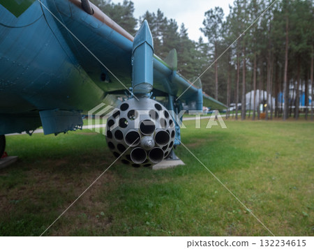 spherical rocket pod profile against pine tree backdrop capturing perforated form and tubular barrels, balanced composition blends industrial design with outdoor museum ambiance and muted 132234615