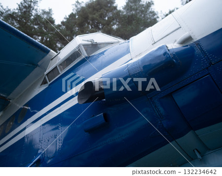 blue fuselage closeup shows tail and livery detail, glossy paint reflecting overcast sky and nearby trees, tight framing emphasizes panel seams, rivets and maintenance access points blue fuselage closeup shows tail and livery detail, glossy paint reflecting overcast sky and nearby trees, tight framing emphasizes panel seams, rivets and maintenance access points 132234642