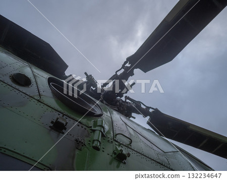 weathered green helicopter rotor in nighttime shot, dramatic lowangle view of helicopter rotor with weathered blades, closeup view of weathered helicopter rotor hub at night from dramatic 132234647