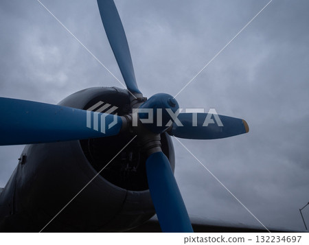 various aircraft stationed outside airport, multiple aircraft types sit grounded under overcast sky, diverse fleet of planes is parked on airport apron amid cloudy weather conditions 132234697