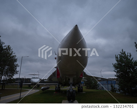 vintage plane exhibit, aircraft display under cloudy sky, museum showcasing vintage aircraft beneath overcast clouds, visitor examines aircraft fuselage on museum walkway in damp landscape 132234701