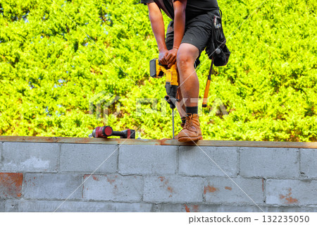Construction worker drills into concrete wall on construction site Construction worker drills into concrete wall on construction site 132235050