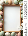 Decorative pastel Easter eggs with gold specks and spring flowers surrounding a wooden frame on a soft beige background, celebrating Easter Space for text 132235202