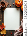 Blank white paper surrounded by pumpkins, coffee, autumn leaves, and fabric on dark wooden table, cozy seasonal concept Space for text 132235203