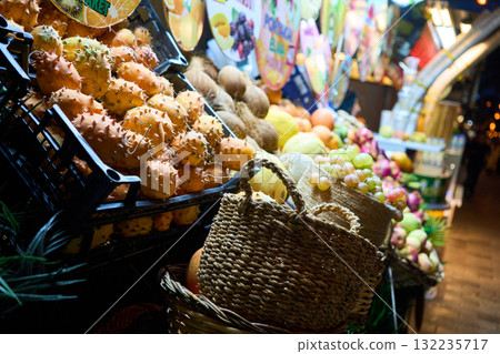 A vibrant display of exotic fruits at a market stall, featuring spiky kiwano melons, grapes, and other colorful produce. 132235717