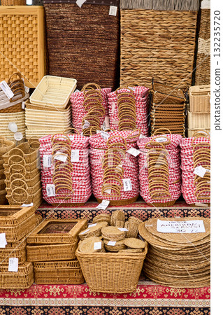 A vibrant display of woven baskets, trays, and coasters at a market, showcasing various shapes and textures. 132235720