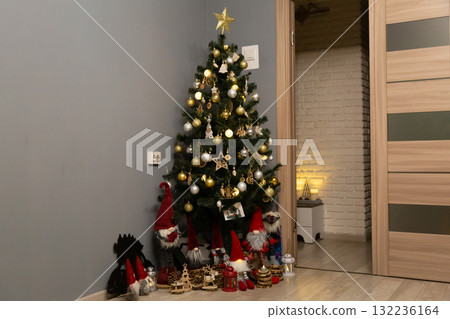 Beautiful Christmas tree decorated with golden ornaments, lights, and a shining star topper. Festive gnome toys placed around the base create a cozy and joyful holiday atmosphere at home Beautiful Christmas tree decorated with golden ornaments, lights, and a shining star topper. Festive gnome toys placed around the base create a cozy and joyful holiday atmosphere at home 132236164