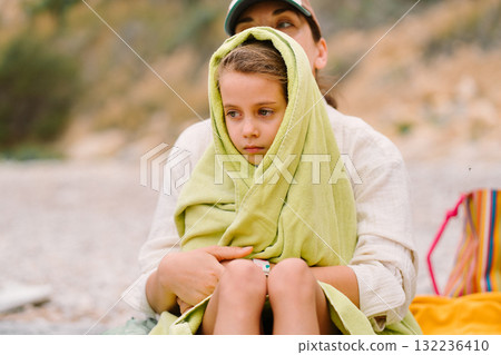 Mother with daughter wrapped in towel sitting 132236410