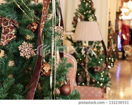 A close-up of a shining Christmas tree and luxurious decorations in a luxurious hotel lobby. Copy space. Commercial background advertising material. A close-up of a shining Christmas tree and luxurious decorations in a luxurious hotel lobby. Copy space. Commercial background advertising material. 132236531
