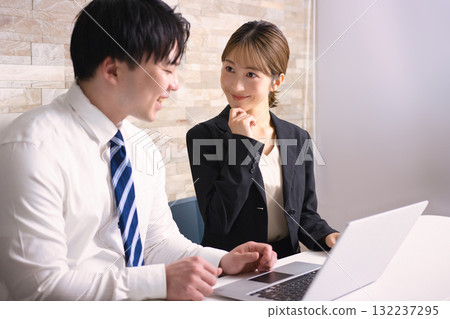 Young men and women having a meeting while looking at a computer in an office Young men and women having a meeting while looking at a computer in an office 132237295