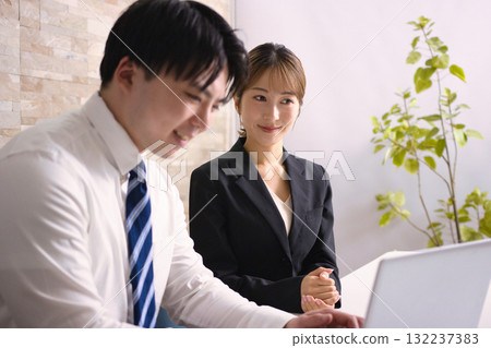 Young men and women having a meeting while looking at a computer in an office 132237383
