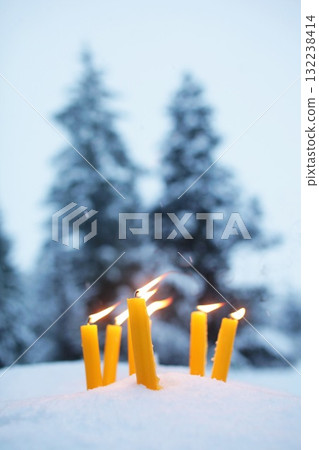 Group of candles are lit in the snow, creating a warm and cozy atmosphere Group of candles are lit in the snow, creating a warm and cozy atmosphere 132238414