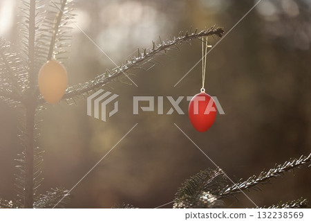 A tree with two red eggs hanging from its branches A tree with two red eggs hanging from its branches 132238569