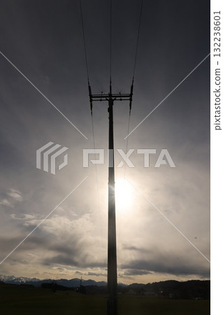 A tall power pole is silhouetted against a cloudy sky 132238601