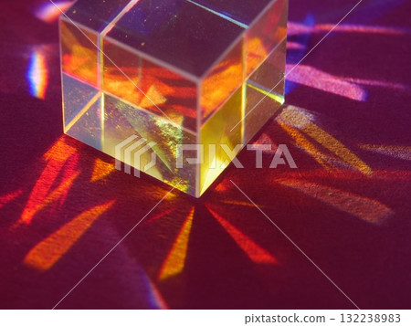 Cube of glass is sitting on a red surface 132238983