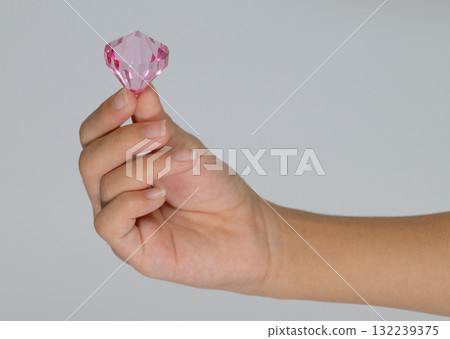 Child's hand holding a pink gem Child's hand holding a pink gem 132239375