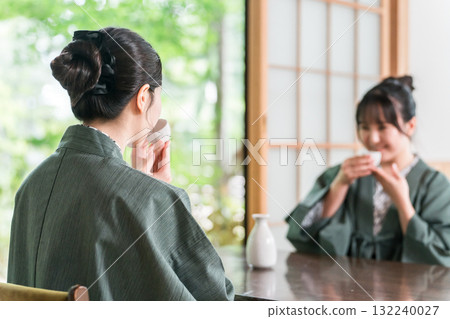 Women and friends drinking sake in yukata on the veranda of a Japanese-style room in a Japanese inn Women and friends drinking sake in yukata on the veranda of a Japanese-style room in a Japanese inn 132240027
