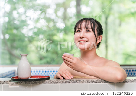 Young Asian woman drinking sake while taking a bath in a hot spring 132240229